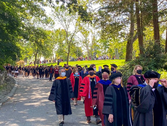 Regis faculty walking down the street to the Fine Arts Center during Commencement