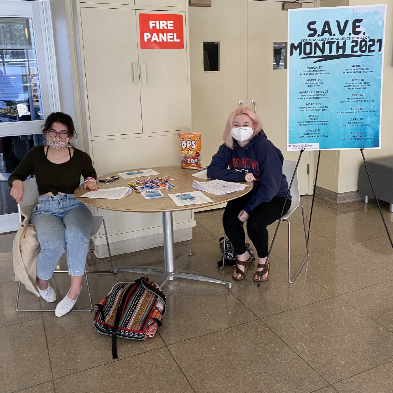 Two students handing out information from SAVE month at the upper student center