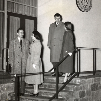 A black and white photo of two couples on the original front steps of Maria Hall