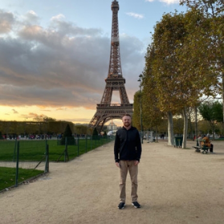 Regis student with Eiffel Tower in distance behind him
