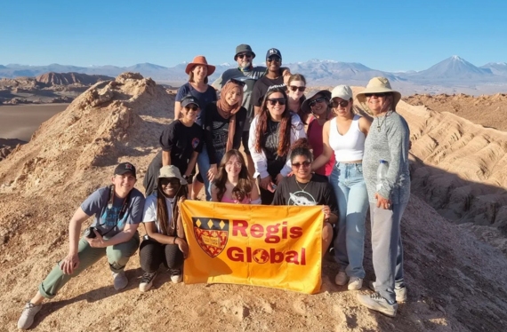 Regis students and faculty pose on a desert mountain peak in Chile, South America during a 10-day immersive learning program