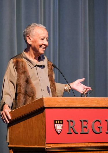 Professor Nikki Giovanni standing at a Regis podium giving her lecture