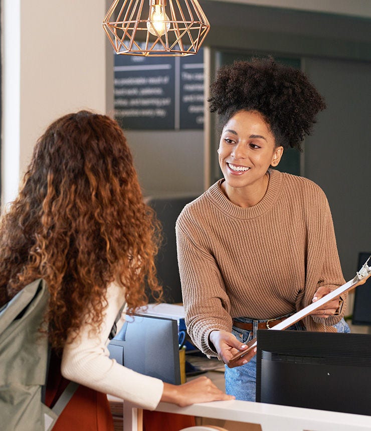 Young woman checks in at front desk, reception, hotel, college library admission; Shutterstock ID 2300147289; purchase_order: -; job: -; client: -; other: -