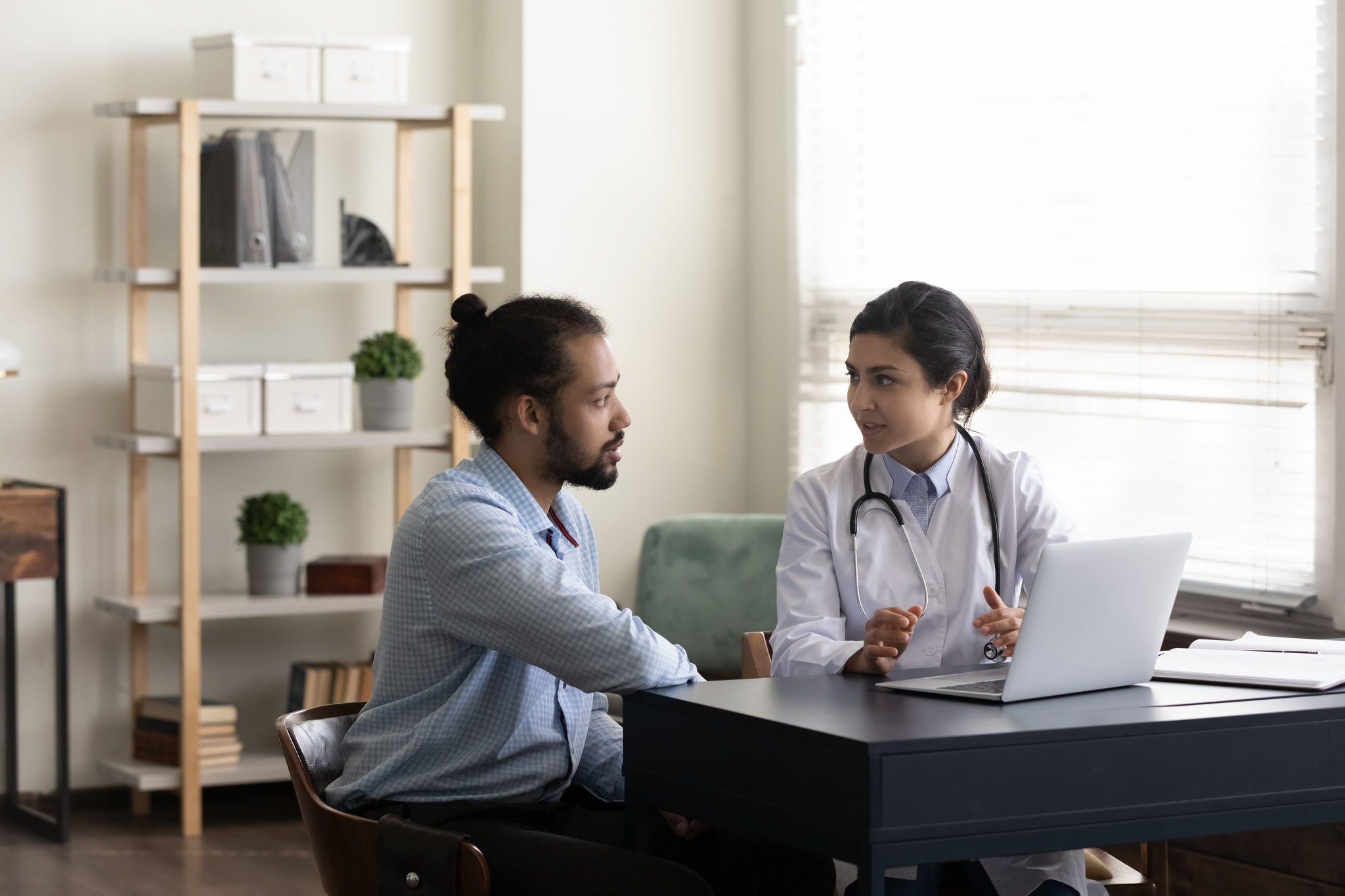 Concentrated skilled young Indian general practitioner doctor explaining test results or illness treatment protocol on computer to African American male patient, medical insurance, healthcare concept.; Shutterstock ID 2107627478; purchase_order: -; job: -; client: -; other: -