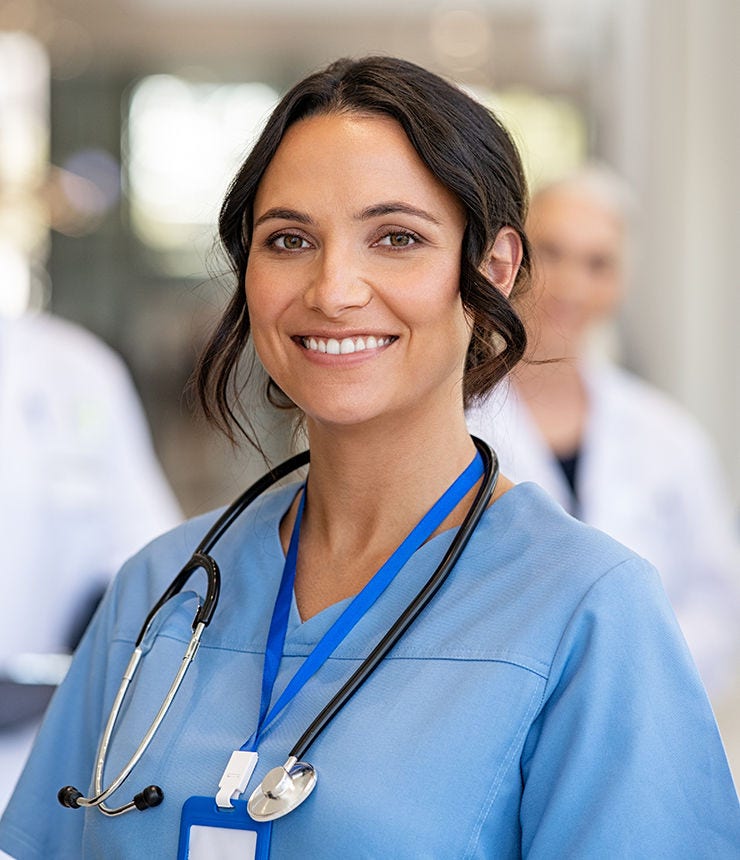 Portrait of happy young nurse in uniform with healthcare team in background. Successful team of doctor and nurses smiling. Beautiful and satisfied healthcare worker in private clinic looking at camera; Shutterstock ID 2054430419; purchase_order: -; job: -; client: -; other: -