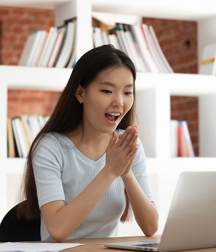 Excited young asian female student sitting at desk in library, looking at computer monitor, received mail with good news, university admission or successful test passing with high score notification.; Shutterstock ID 1470546173; purchase_order: -; job: -; client: -; other: -