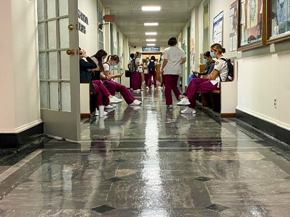 Regis nursing students in scrubs fill the hallway in College Hall before class