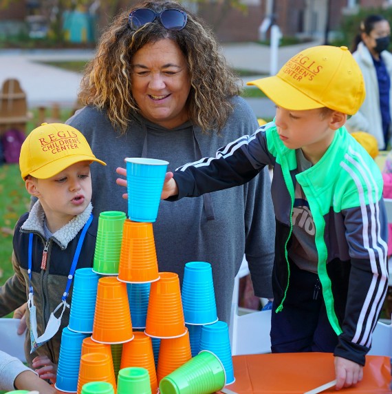 Children's Center Director Rebecca Putnam watches two students build a tower out of plastic cups