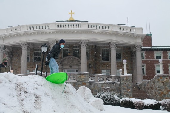 A student snow-surfing in front of College Hall on the Weston campus