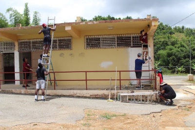 Regis students paint a building during their service trip