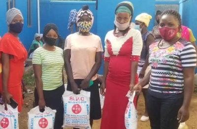 Five Ugandan women pose for a photo after collecting bags of flour