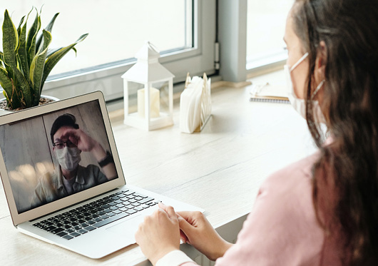 A woman wearing a medical mask on a video call with a man also wearing a medical mask.