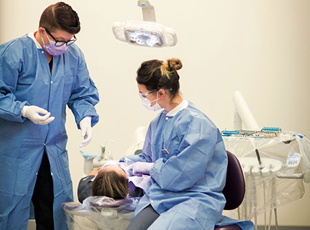 Two Regis Dental Hygiene students working on a patient