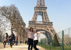 Two students stand in front of the Eiffel Tower in Paris