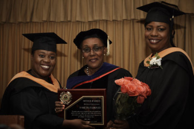 Three graduates of the Regis College Haiti Project pose with an award