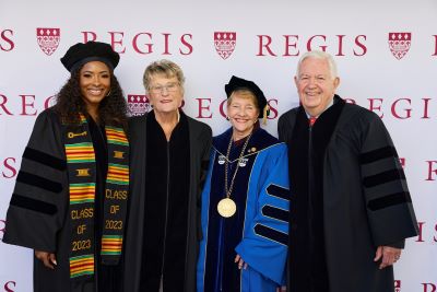 Four people smiling wearing academic regalia
