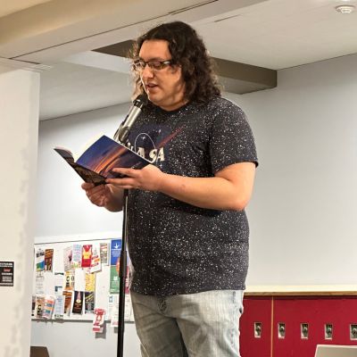 Image of Jacob Pardo reading from a book on the Regis Campus