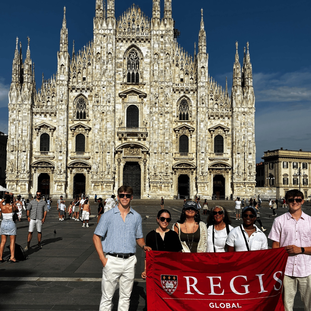 students hold red flag in front of the Duomo
