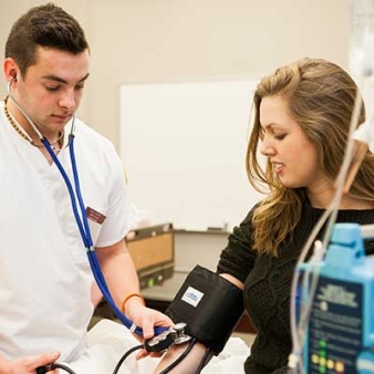 Male nursing student taking blood pressure