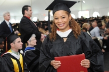 Yanina Vasquez, a Regis North student, in her graduation gown holding her diploma at the Commencement ceremony.