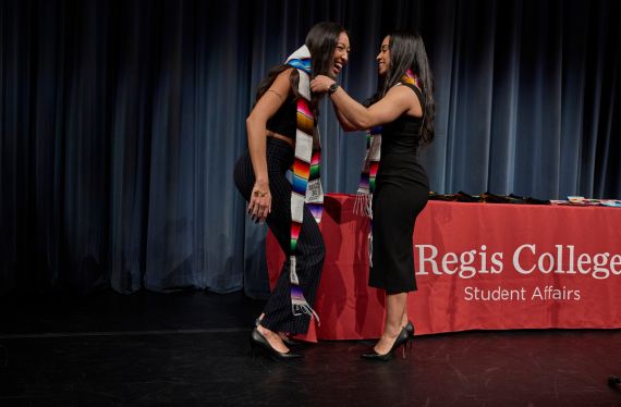 two students on stage receiving their Serape stole
